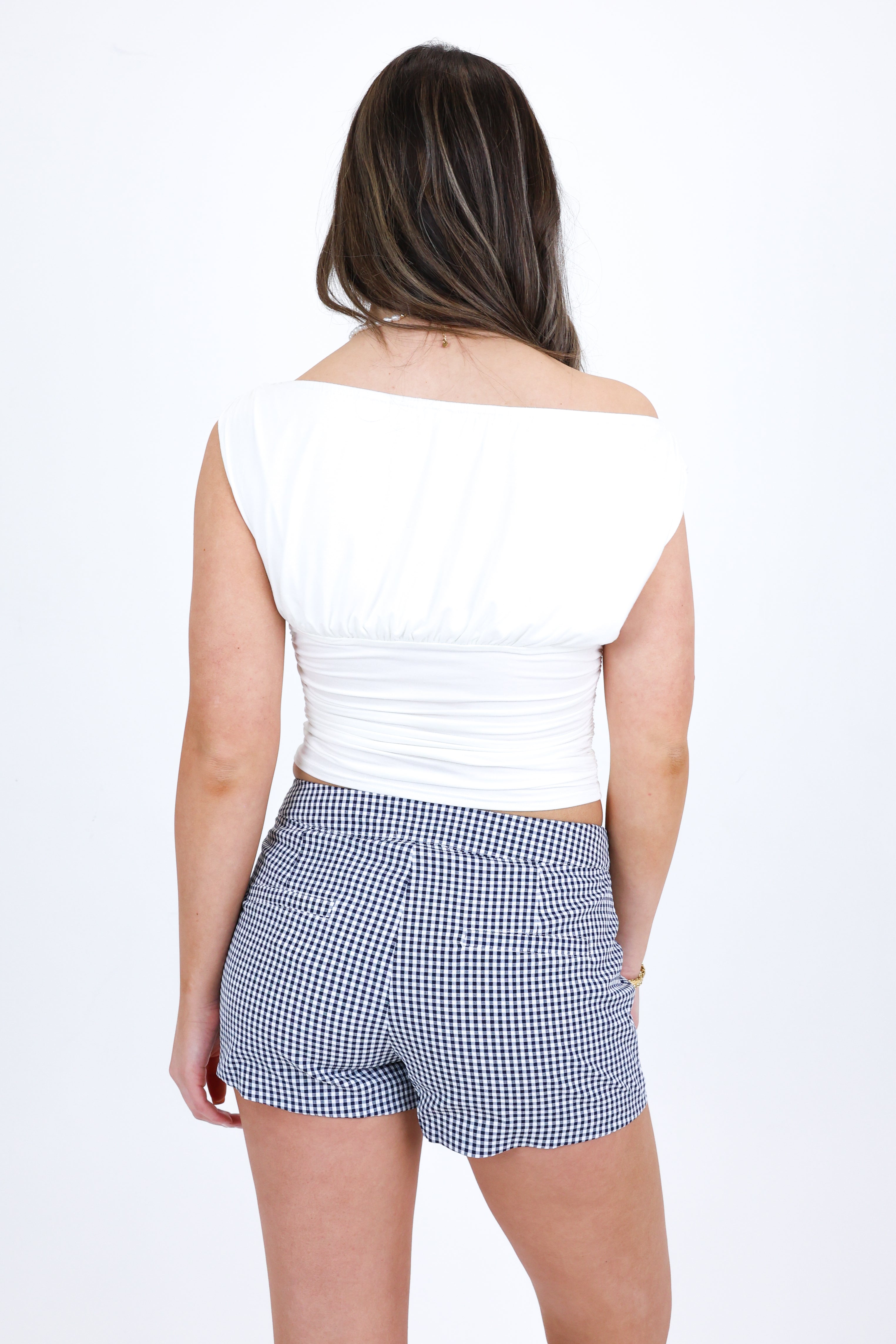 Woman wearing a white top and blue checkered shorts on a white background
