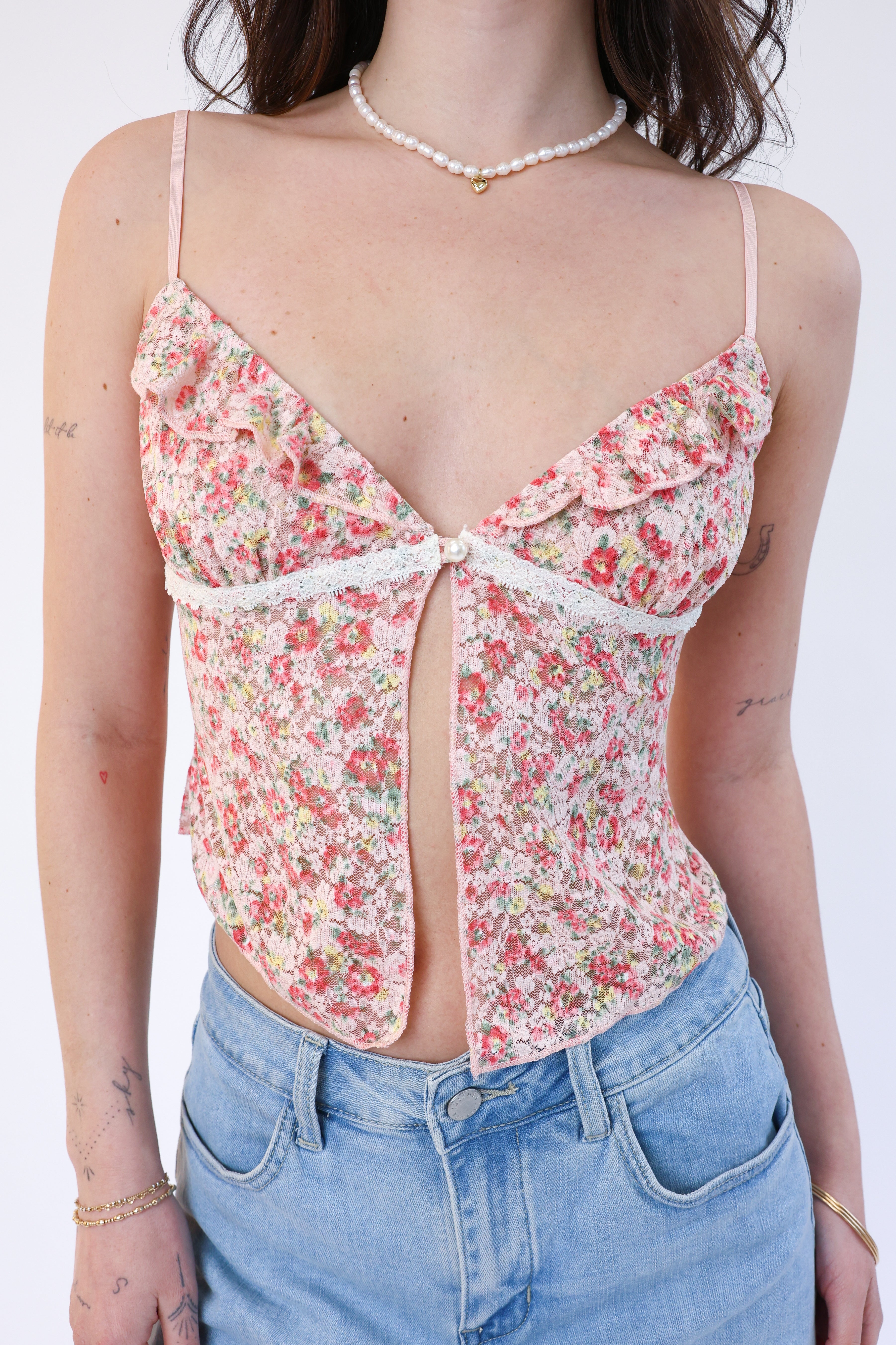 Person wearing a floral top and blue jeans on a white background