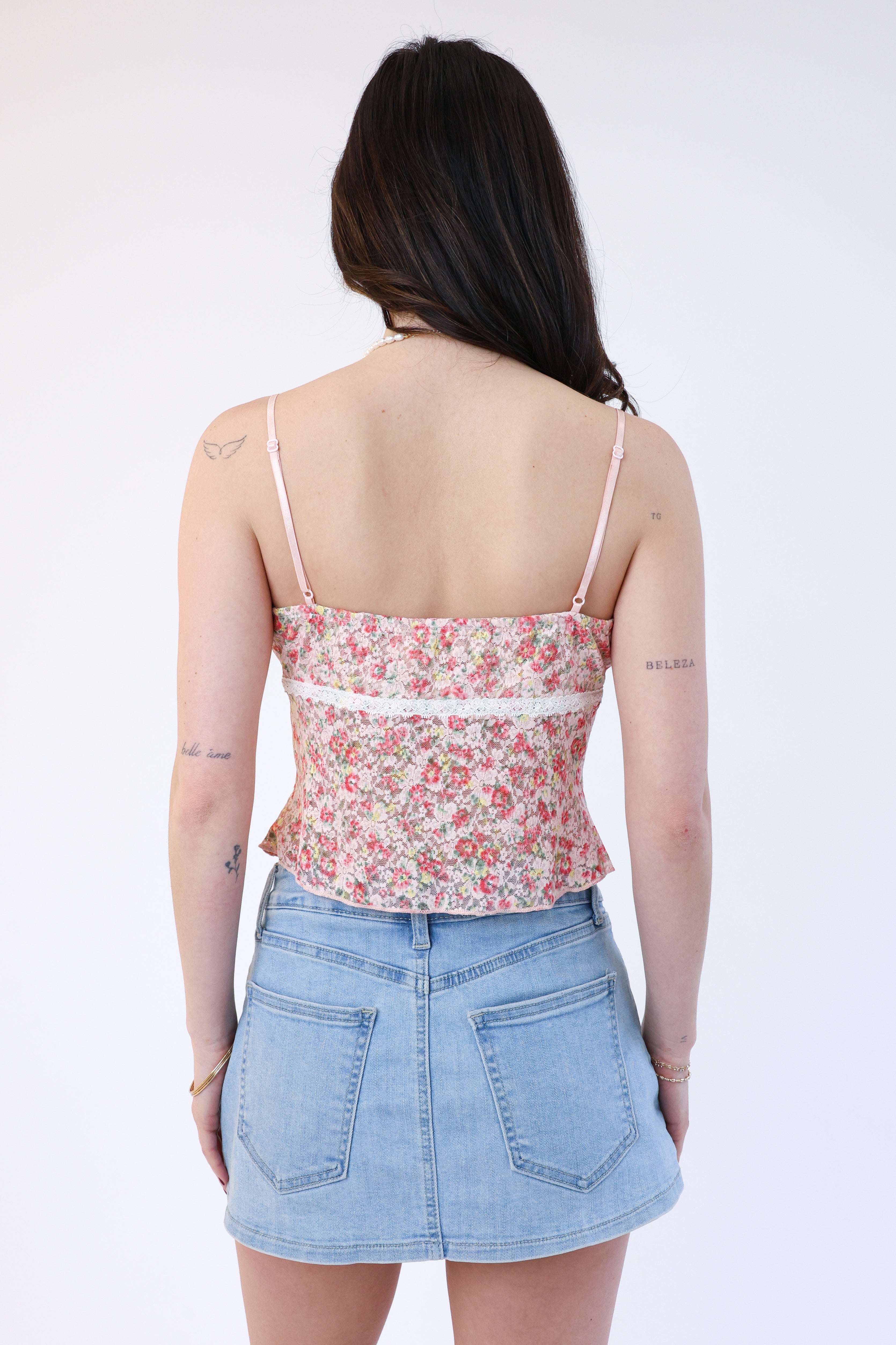 Woman wearing a floral top and denim skirt on a white background