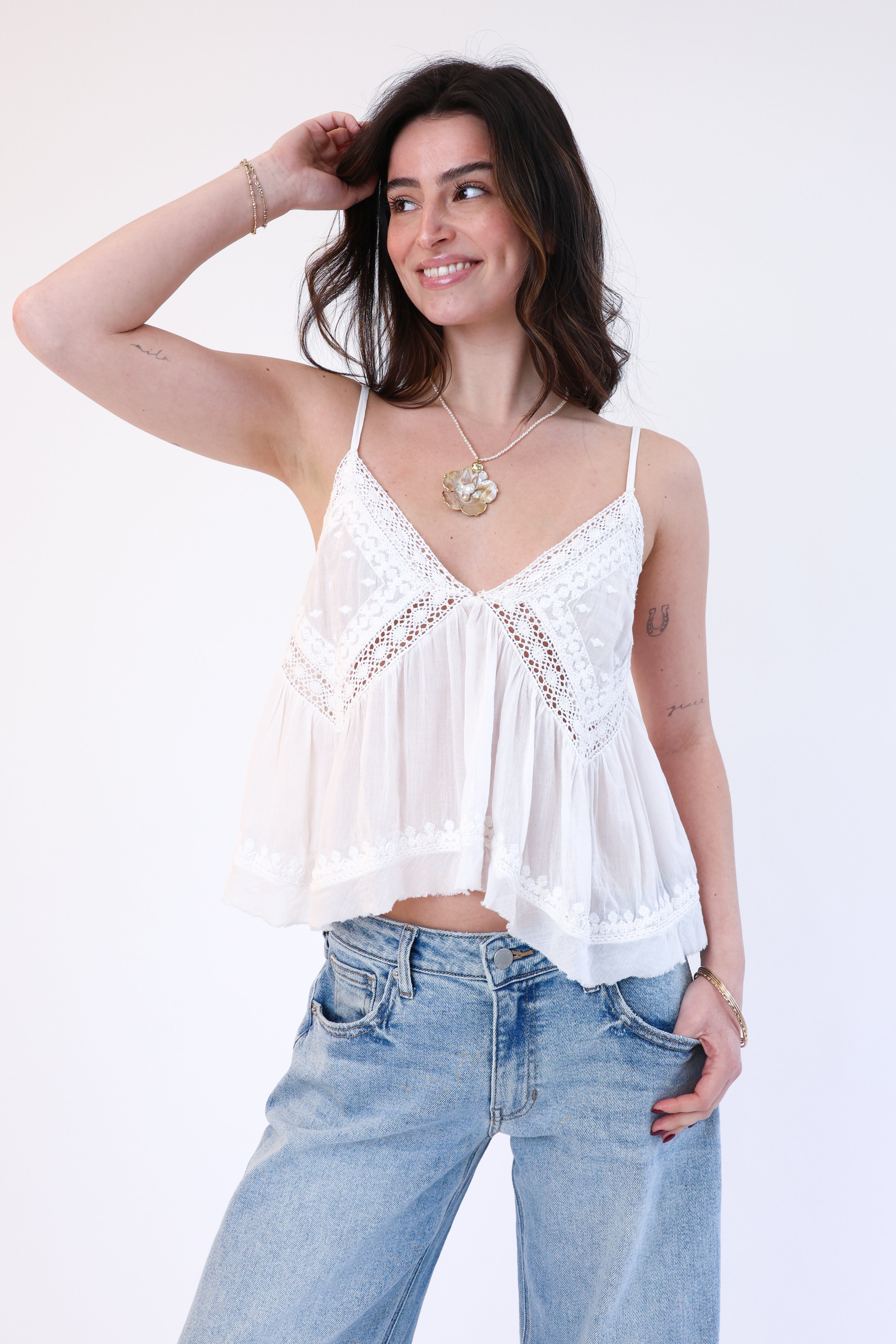 Woman wearing a white lace top and blue jeans on a white background