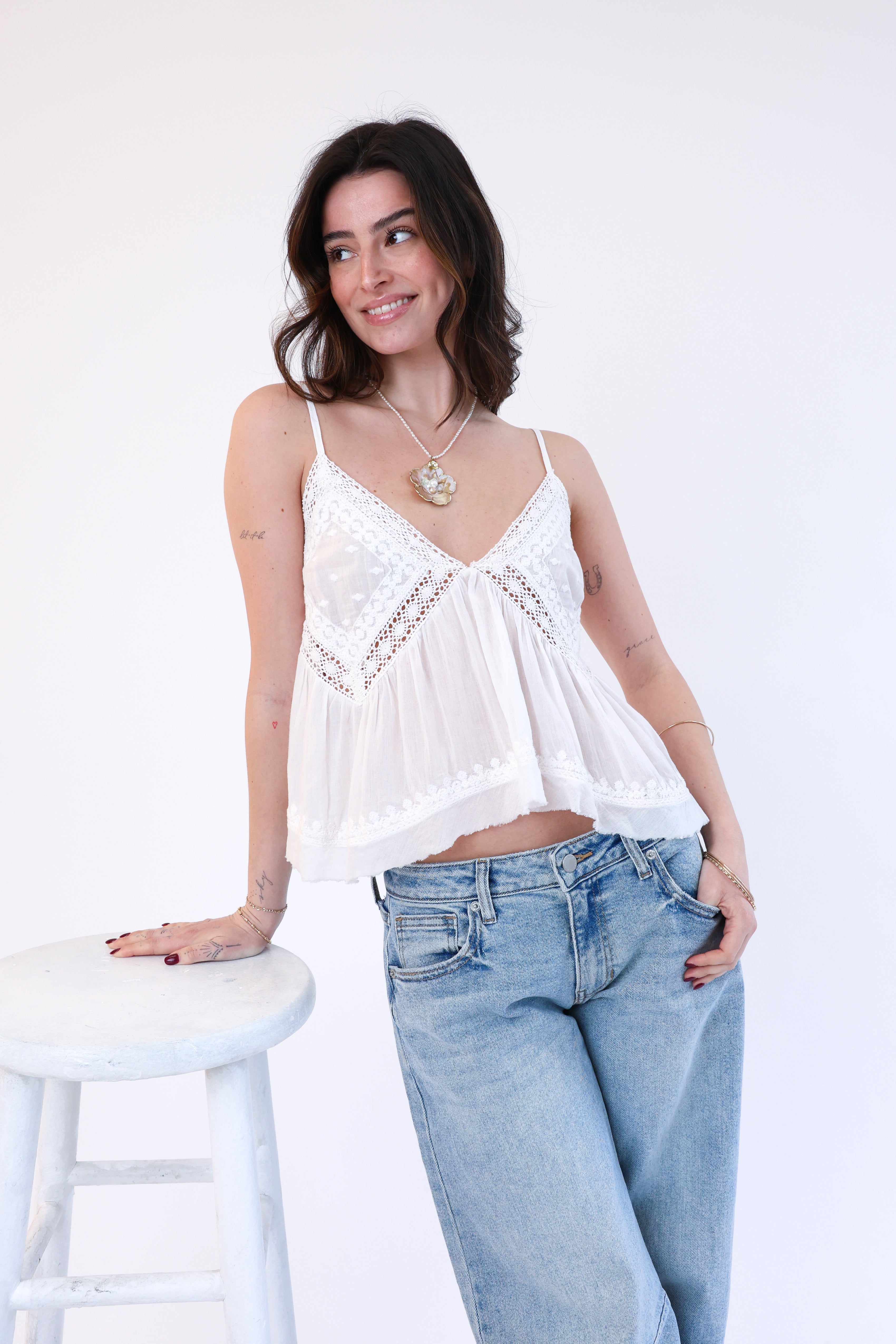 Woman wearing a white top and blue jeans against a white background