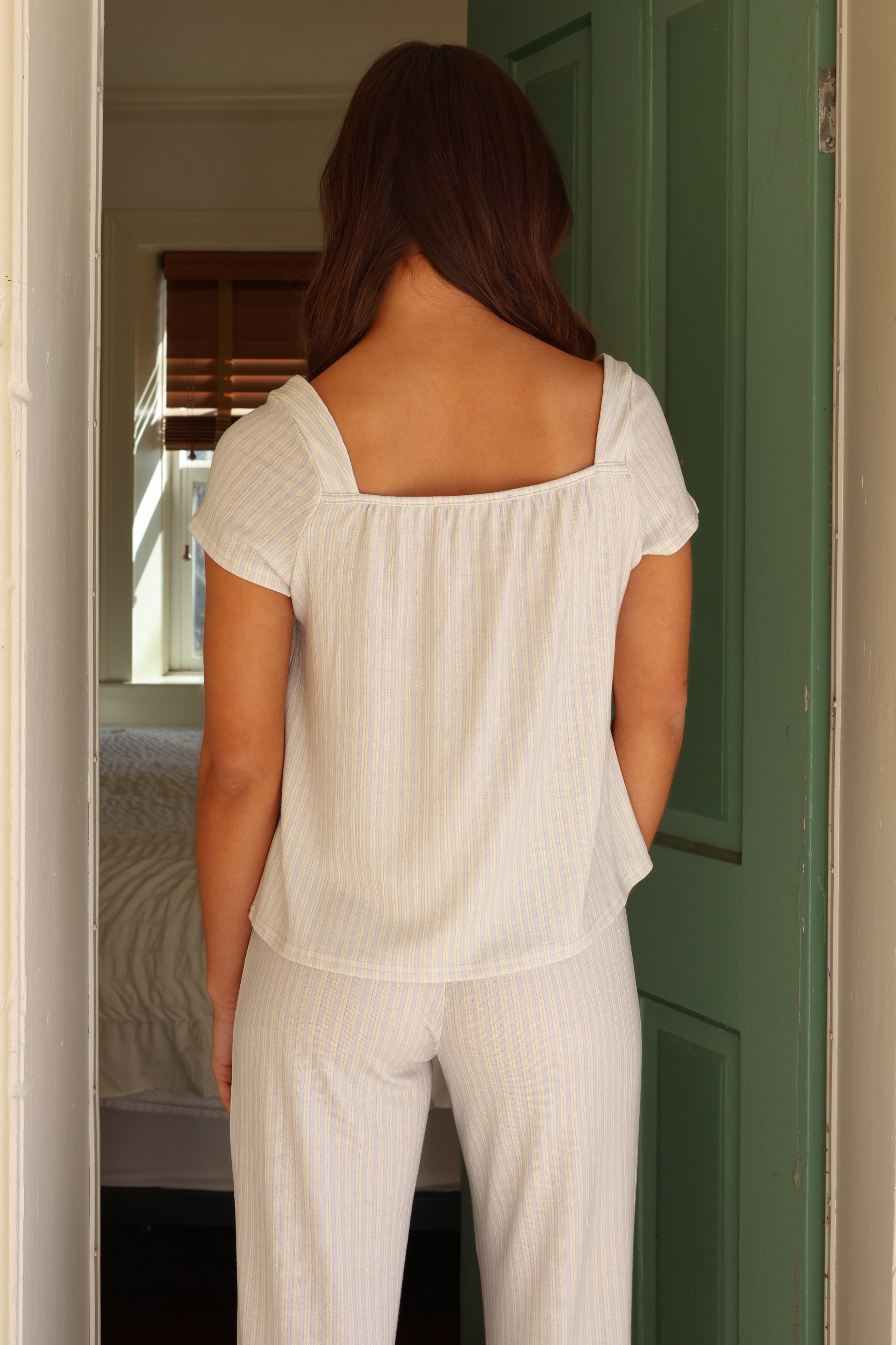 Woman in white pajamas standing in a doorway