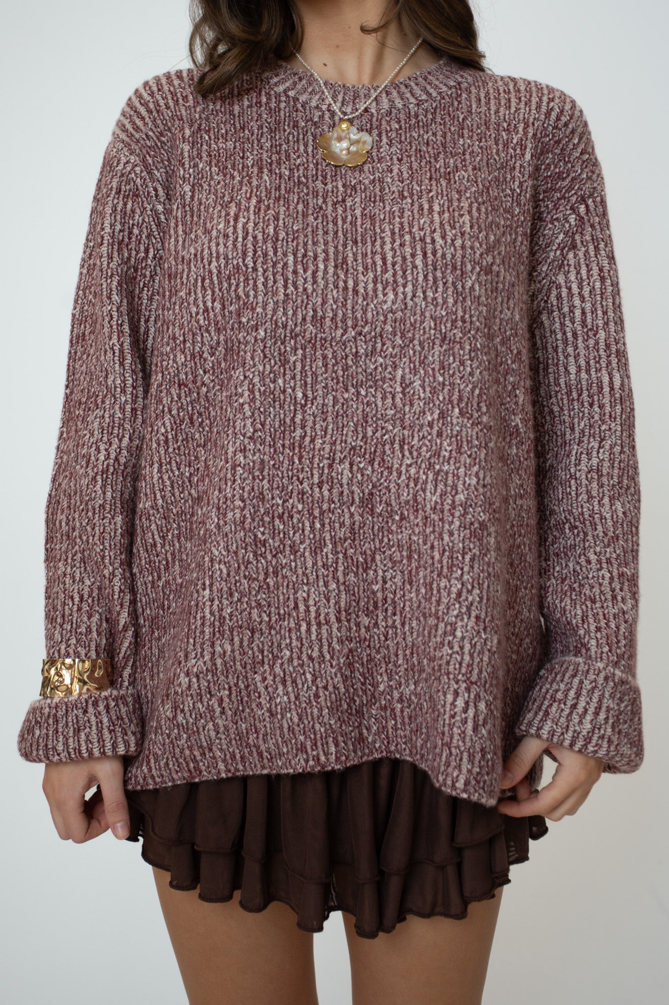 Person wearing a maroon sweater and brown skirt on a plain background