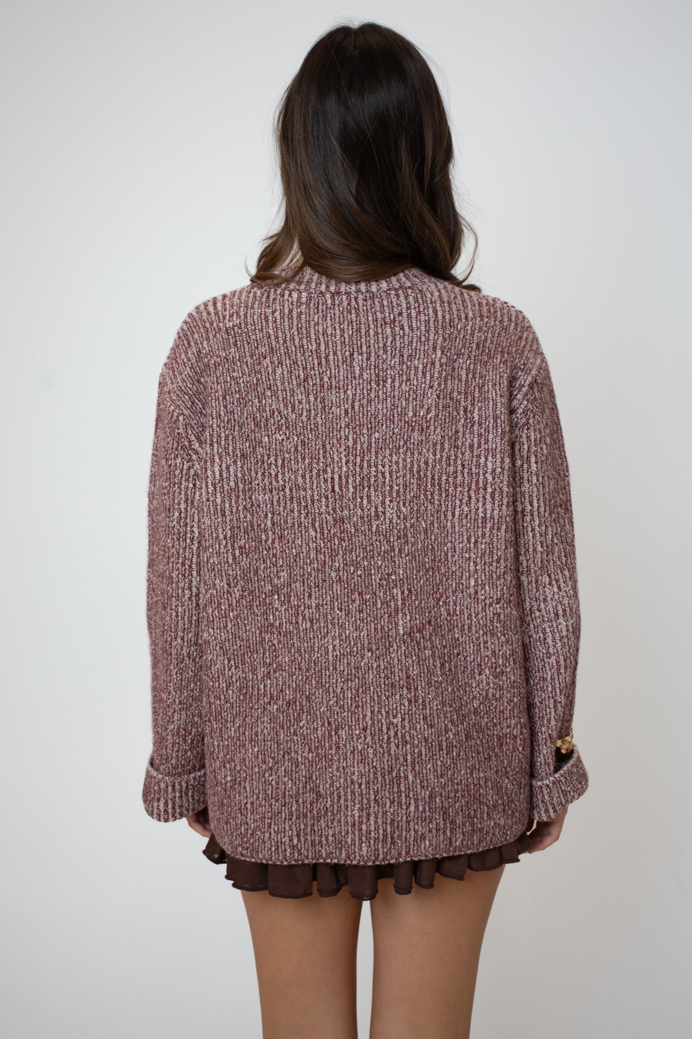 Person wearing a brown knitted sweater with a plain background