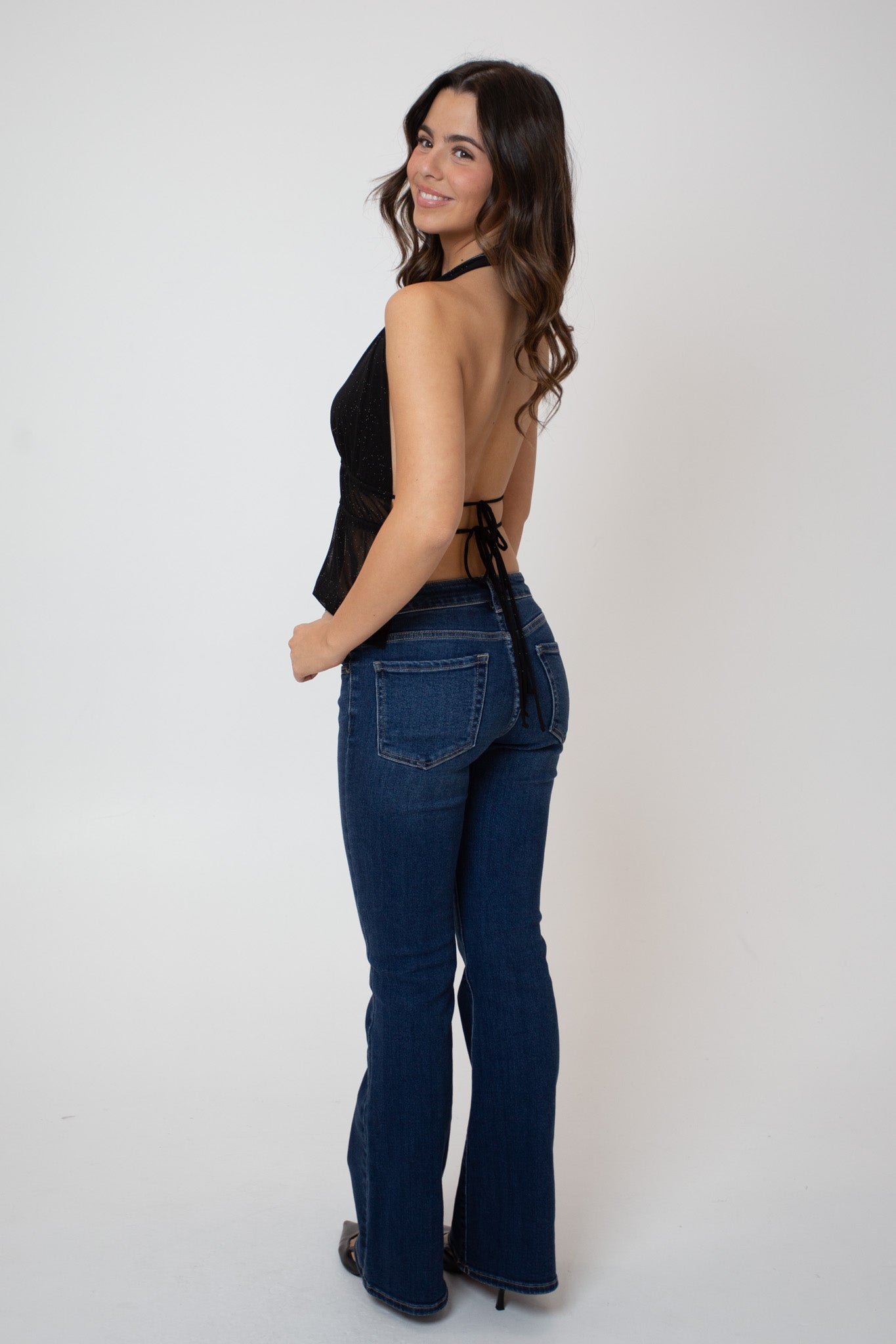 Woman wearing a black top and blue jeans on a white background
