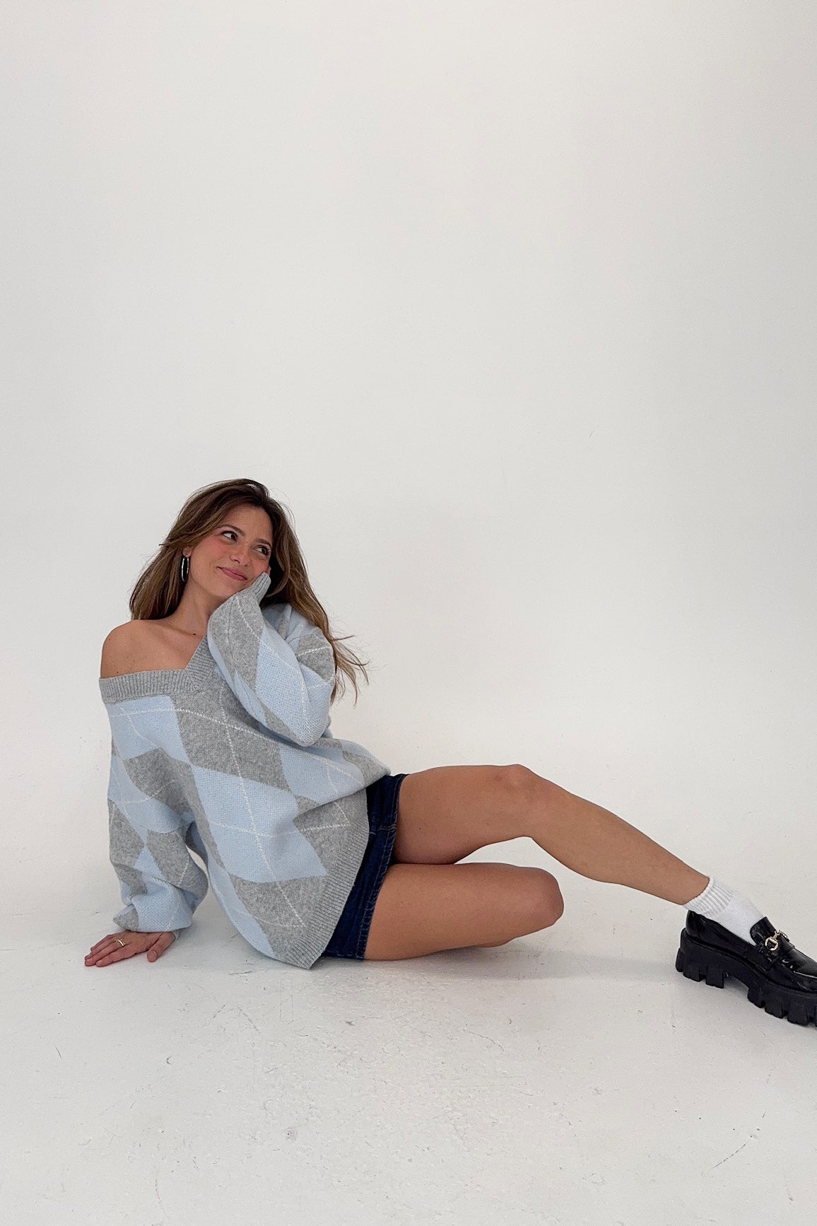 Woman wearing a patterned sweater over a dress on a white background