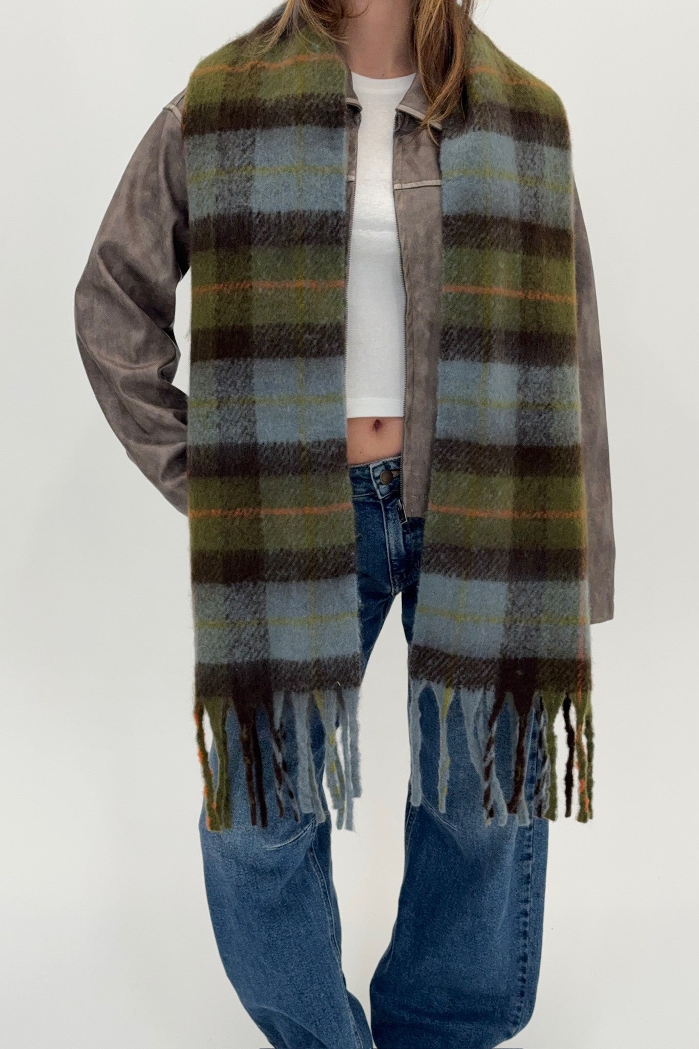 Person wearing a plaid scarf with fringes on a white background