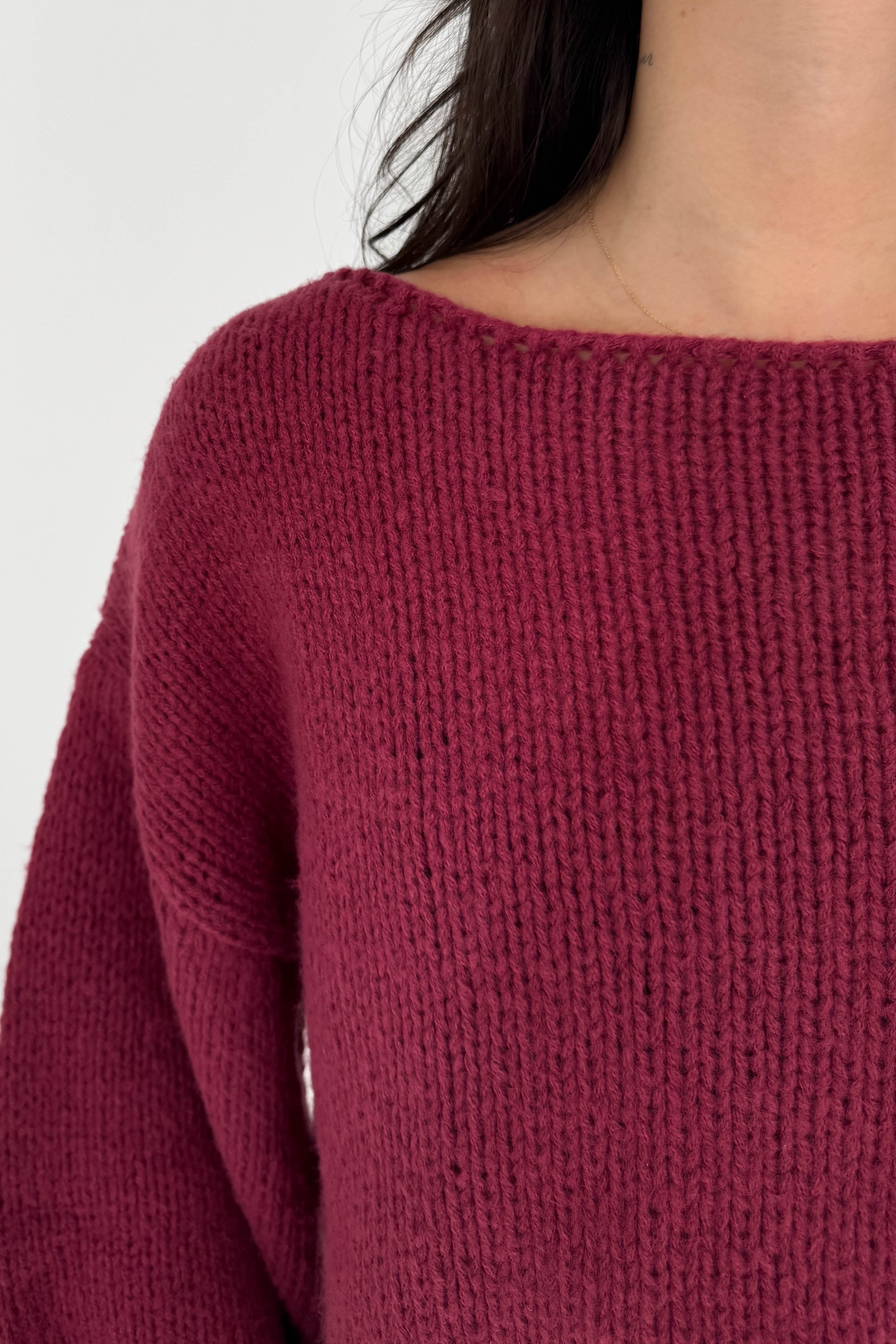 Close-up of a maroon knitted sweater on a plain background