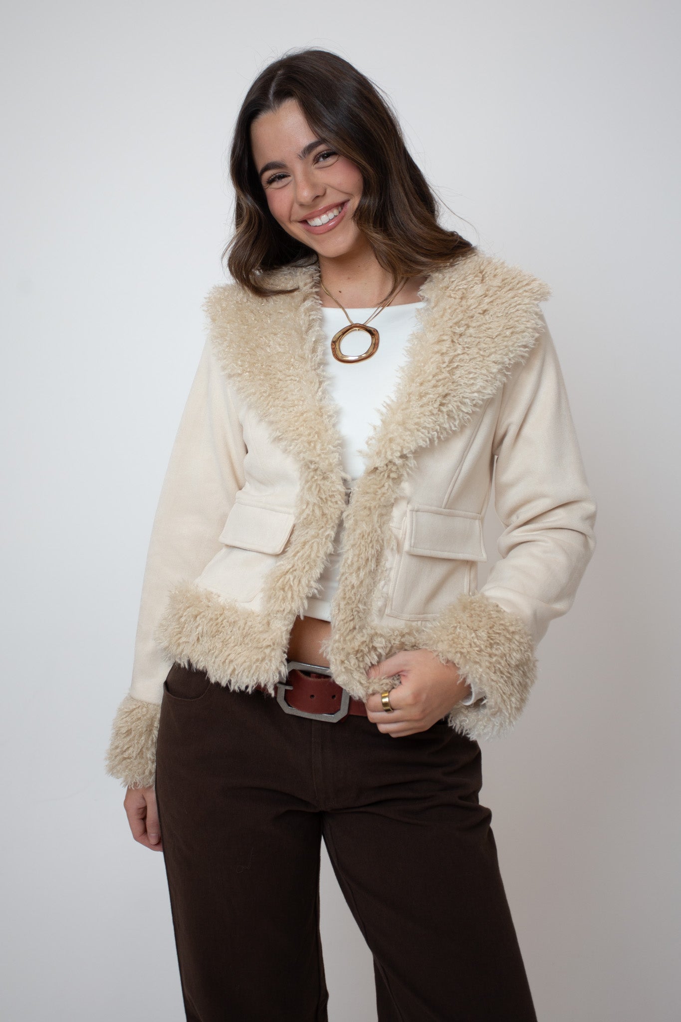 Woman wearing a cream sherpa jacket with a white background