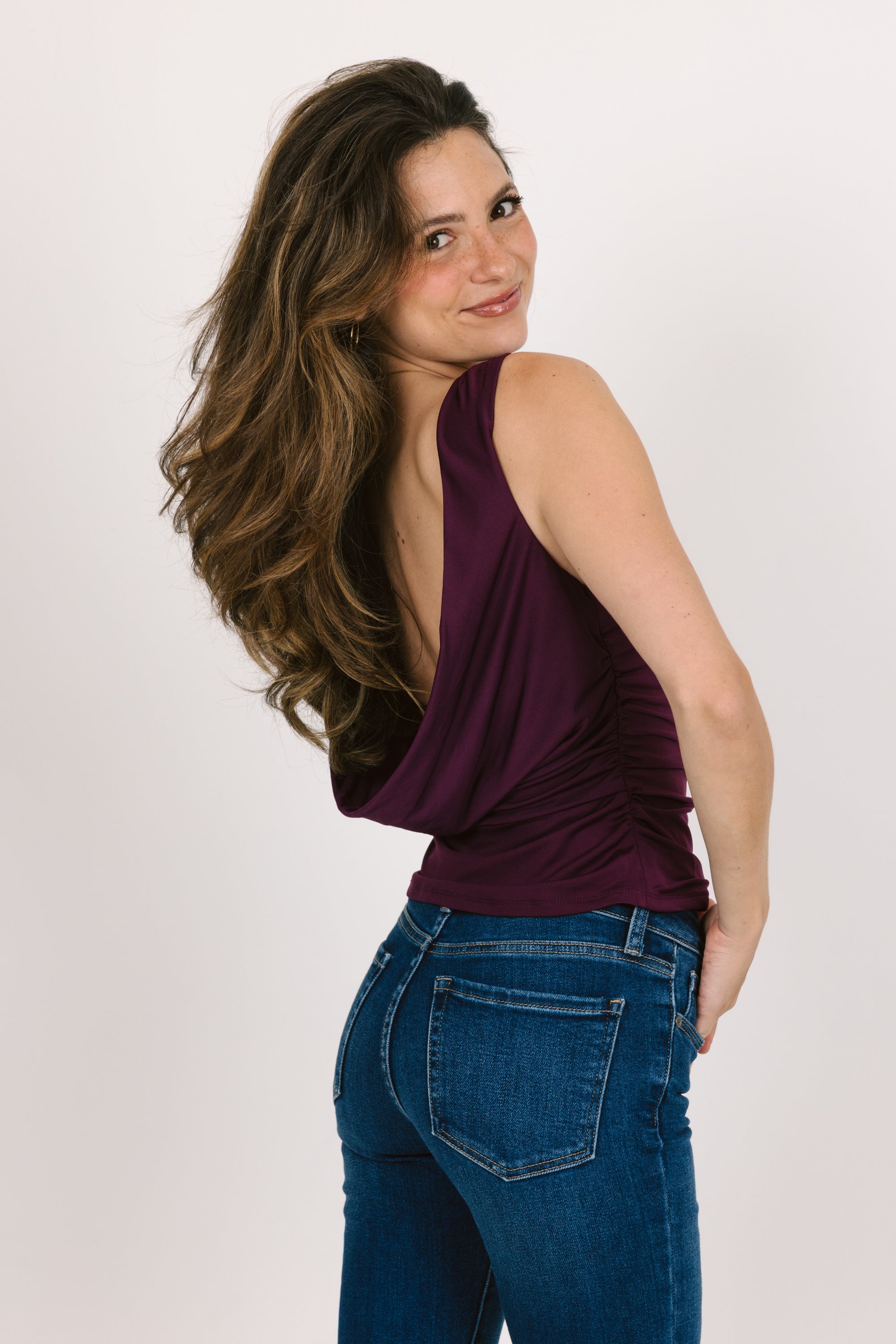 Woman wearing a purple top and blue jeans on a white background