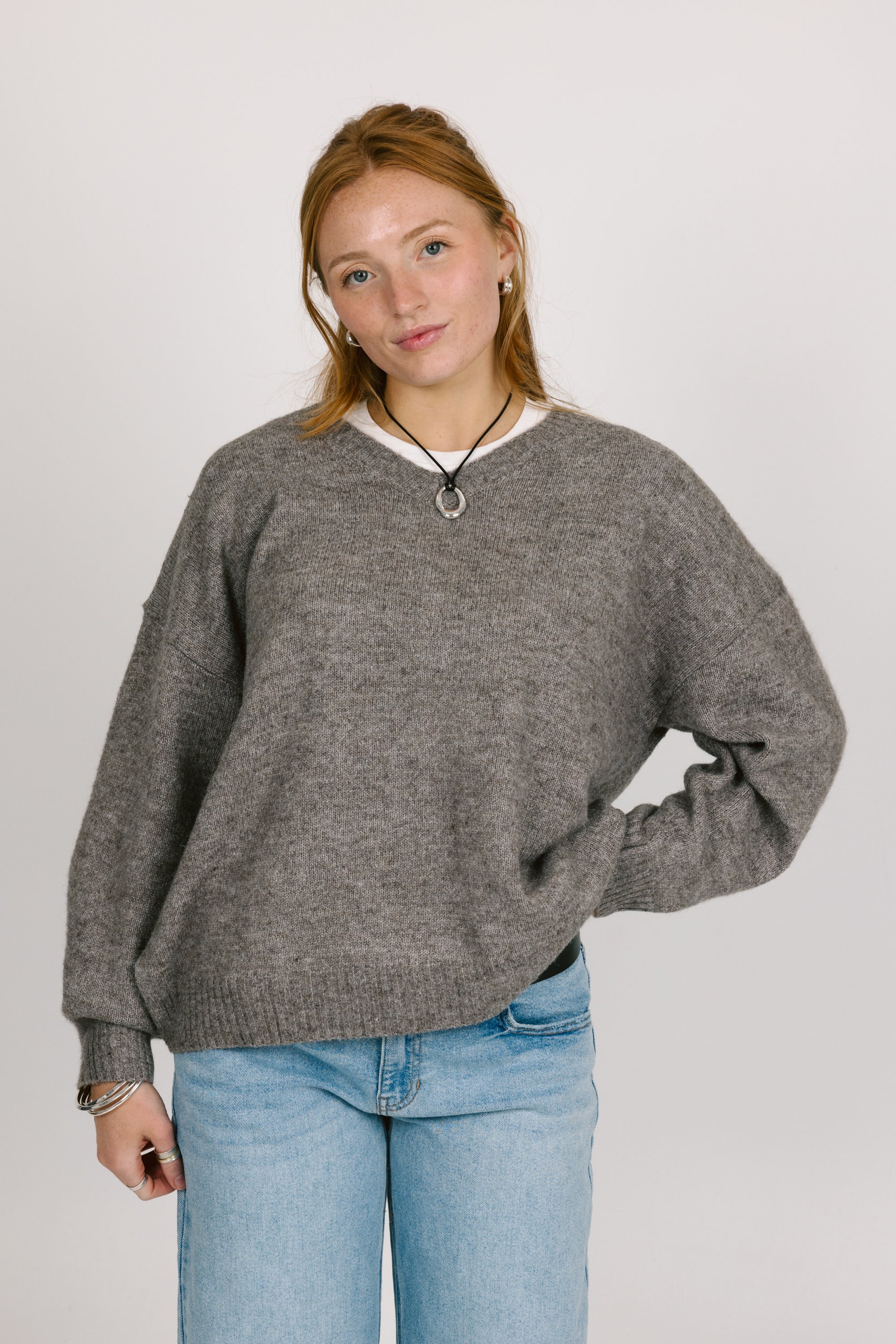 Person wearing a gray sweater and blue jeans against a plain background
