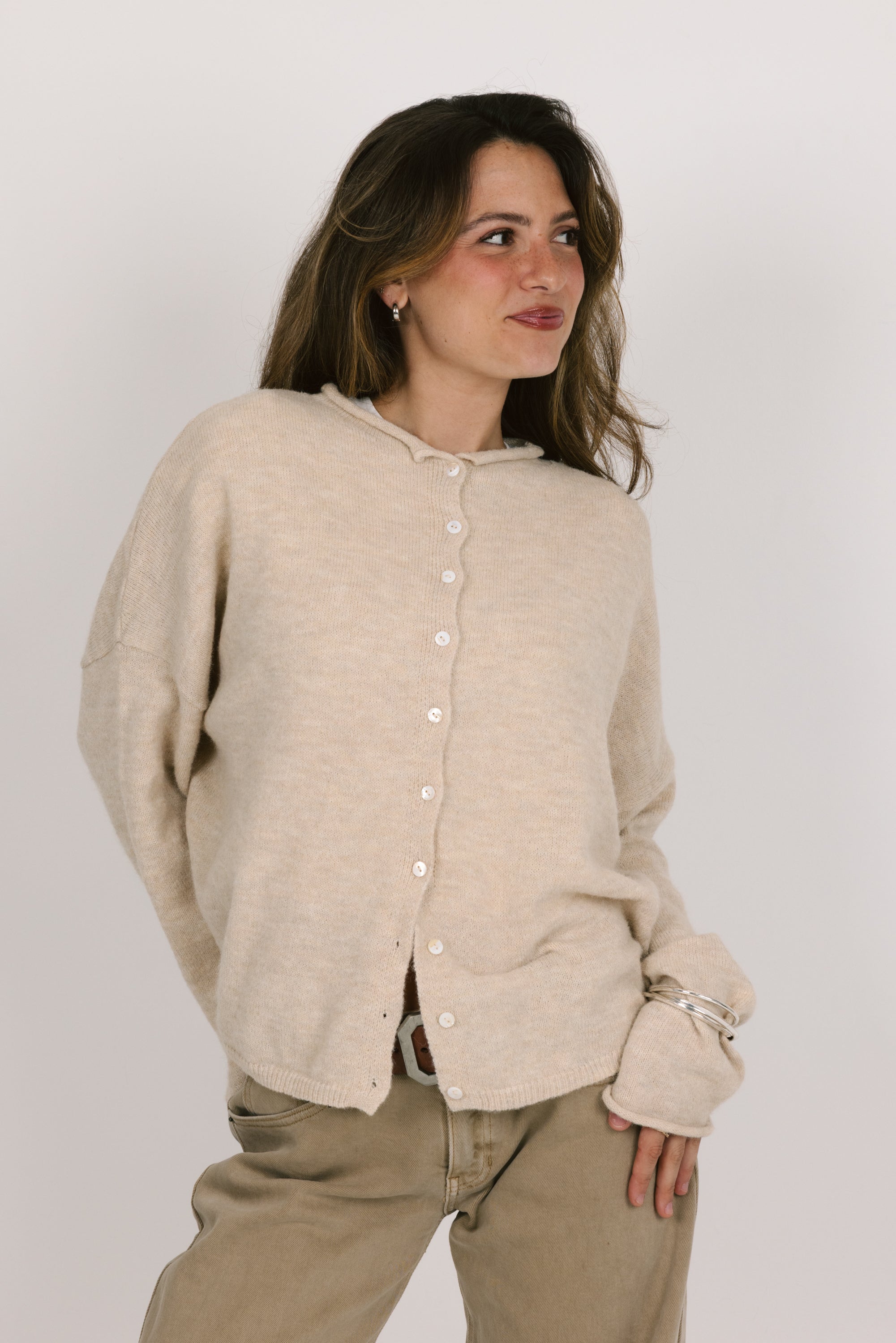 Woman wearing a beige cardigan and pants against a white background