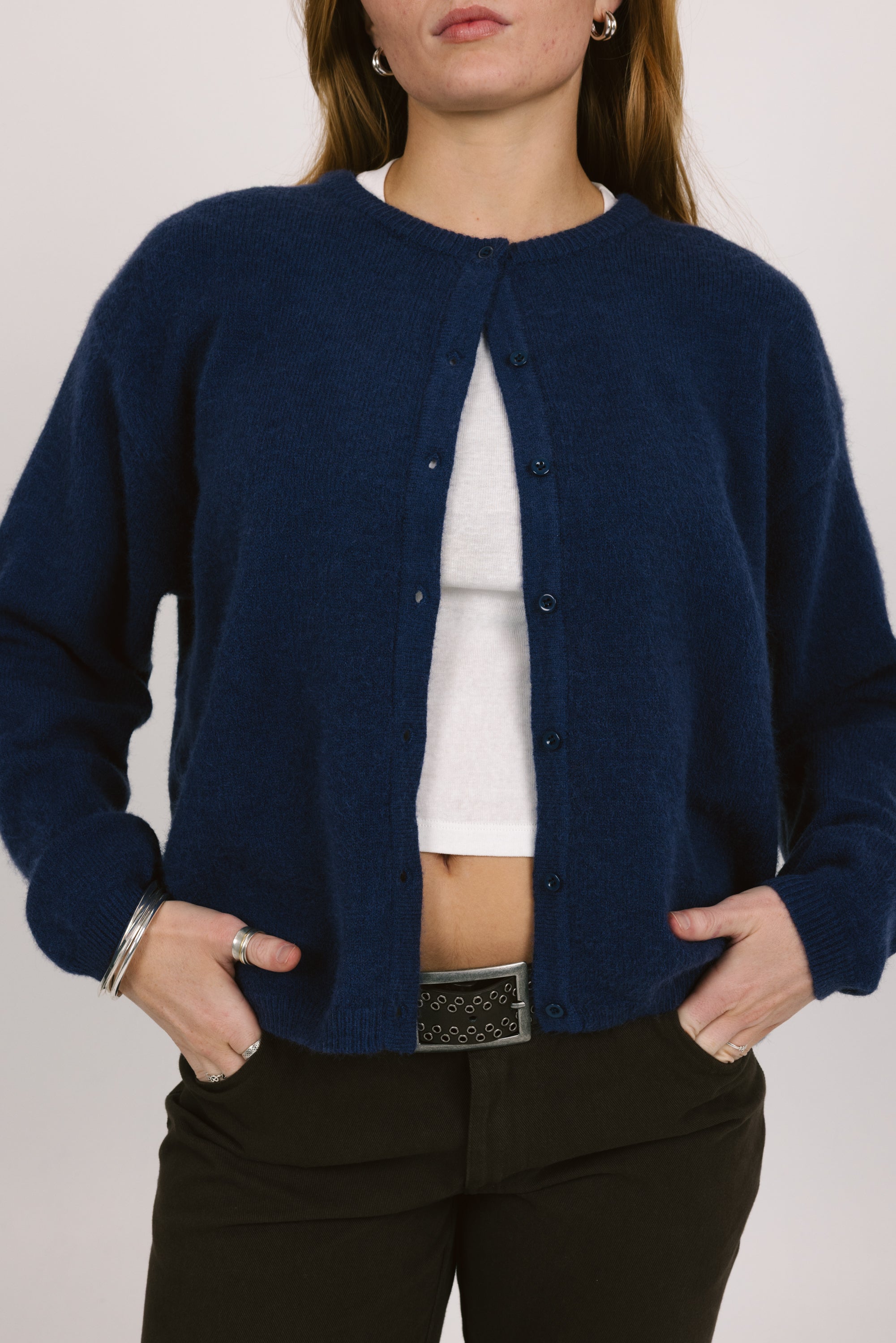 Person wearing a navy blue cardigan over a white shirt with a plain background