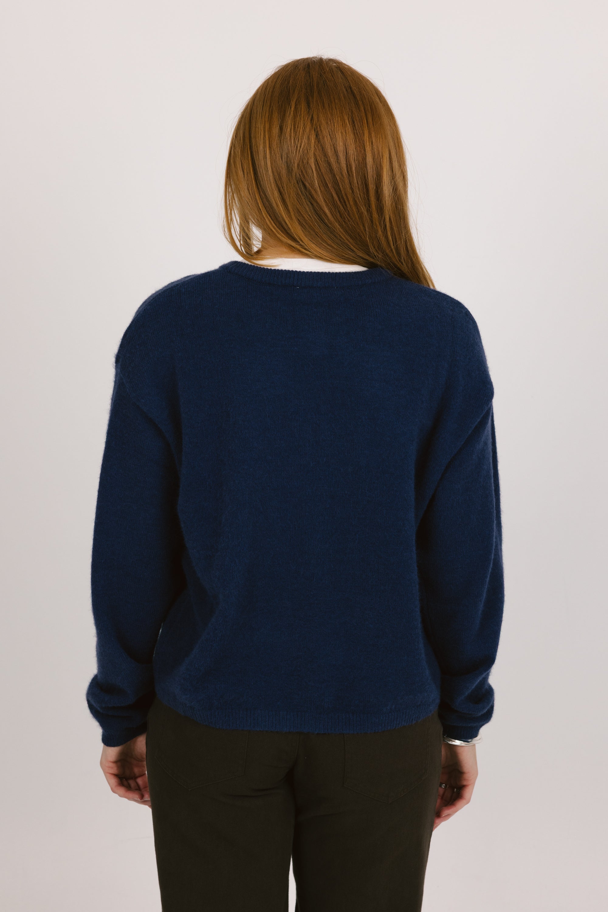 Person wearing a navy blue sweater against a white background