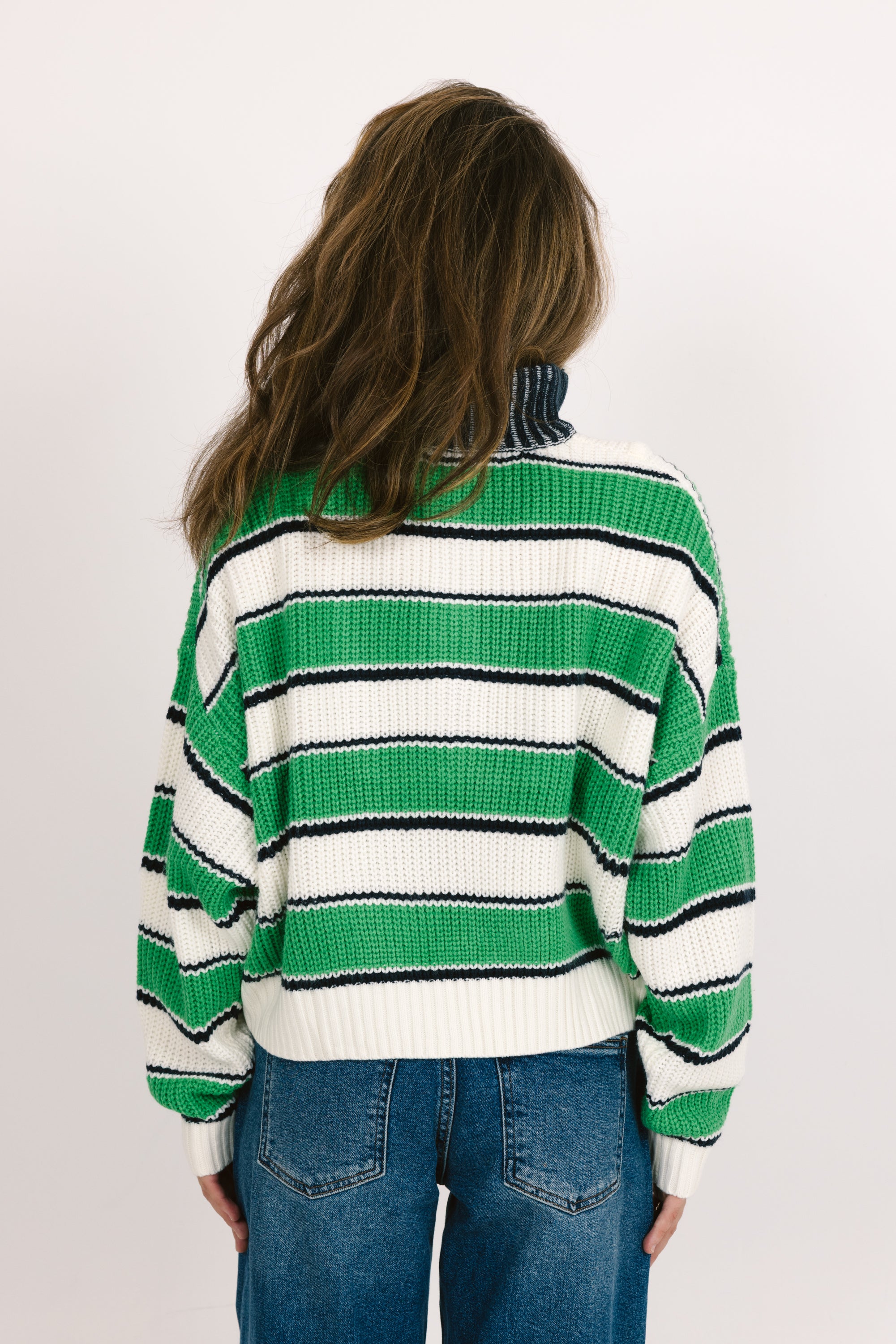 Person wearing a green and white striped sweater on a plain background