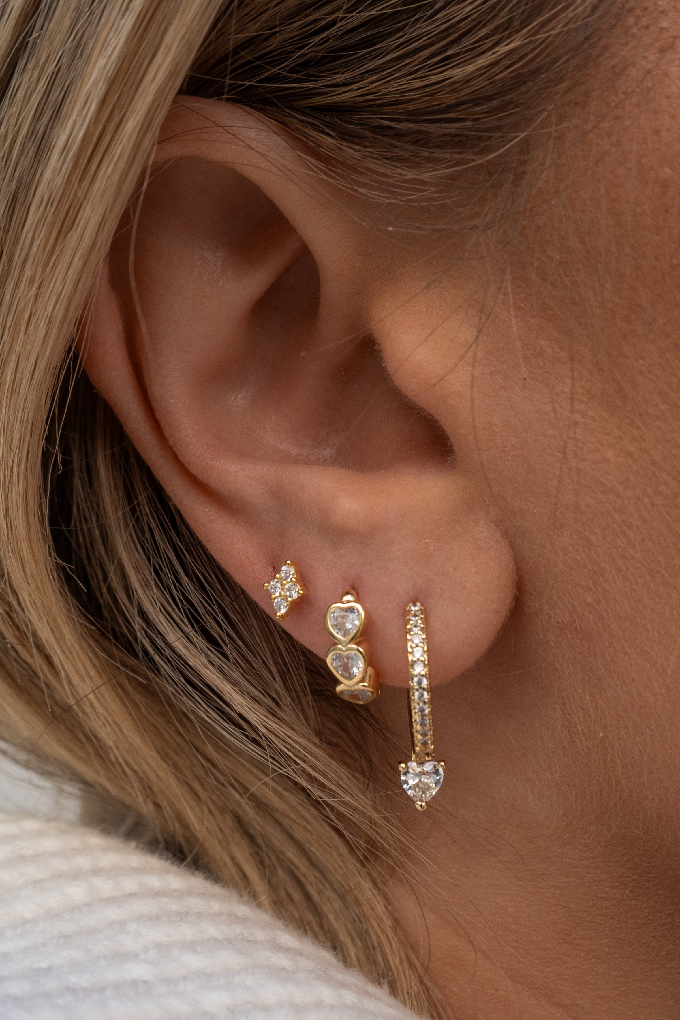 Close-up of an ear wearing gold earrings with a blurred background